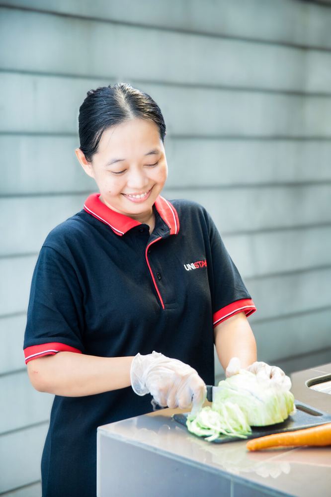 A Unistarr helper in uniform preparing food in the kitchen